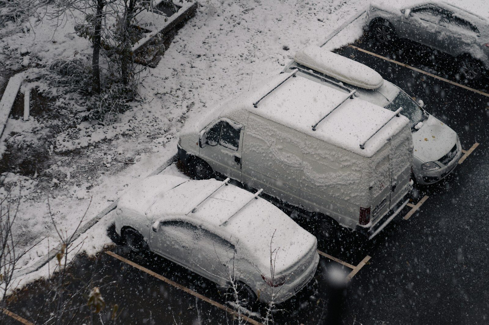 A parking lot covered in snow next to parked cars